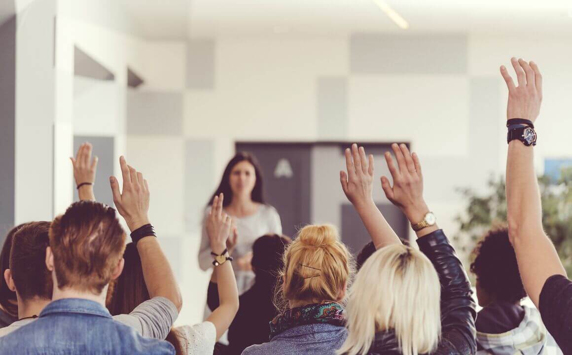 People raising hands in a meeting