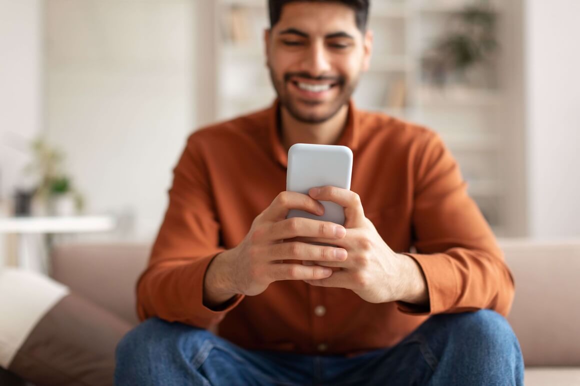 A man holding his phone while sitting on a couch